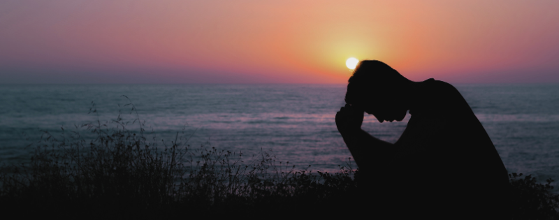 Person praying with hands representing spiritual trauma healing