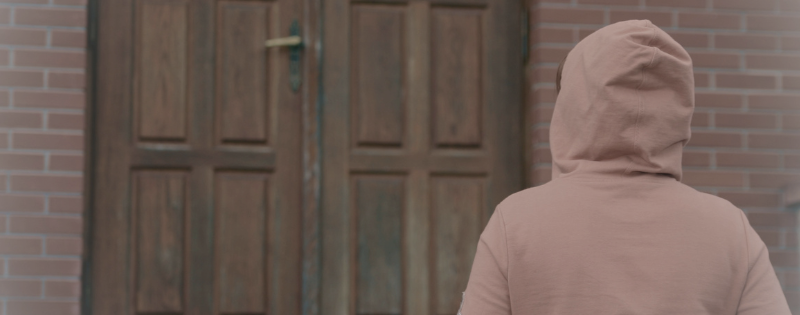 Person standing outside church doors hesitating, feeling judged at church before walking in